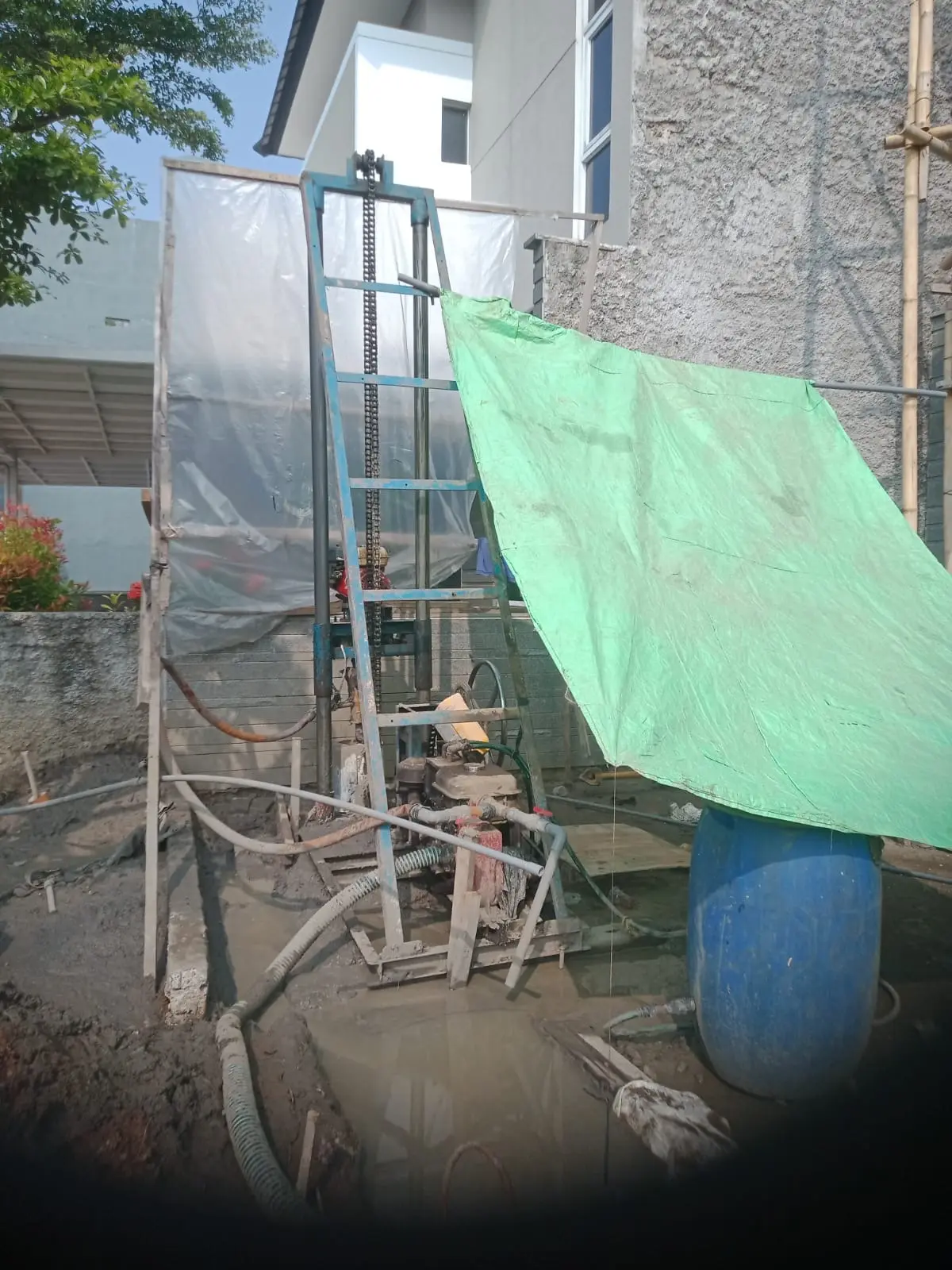 Rig pengeboran sumur bor terpasang di lahan sempit samping rumah